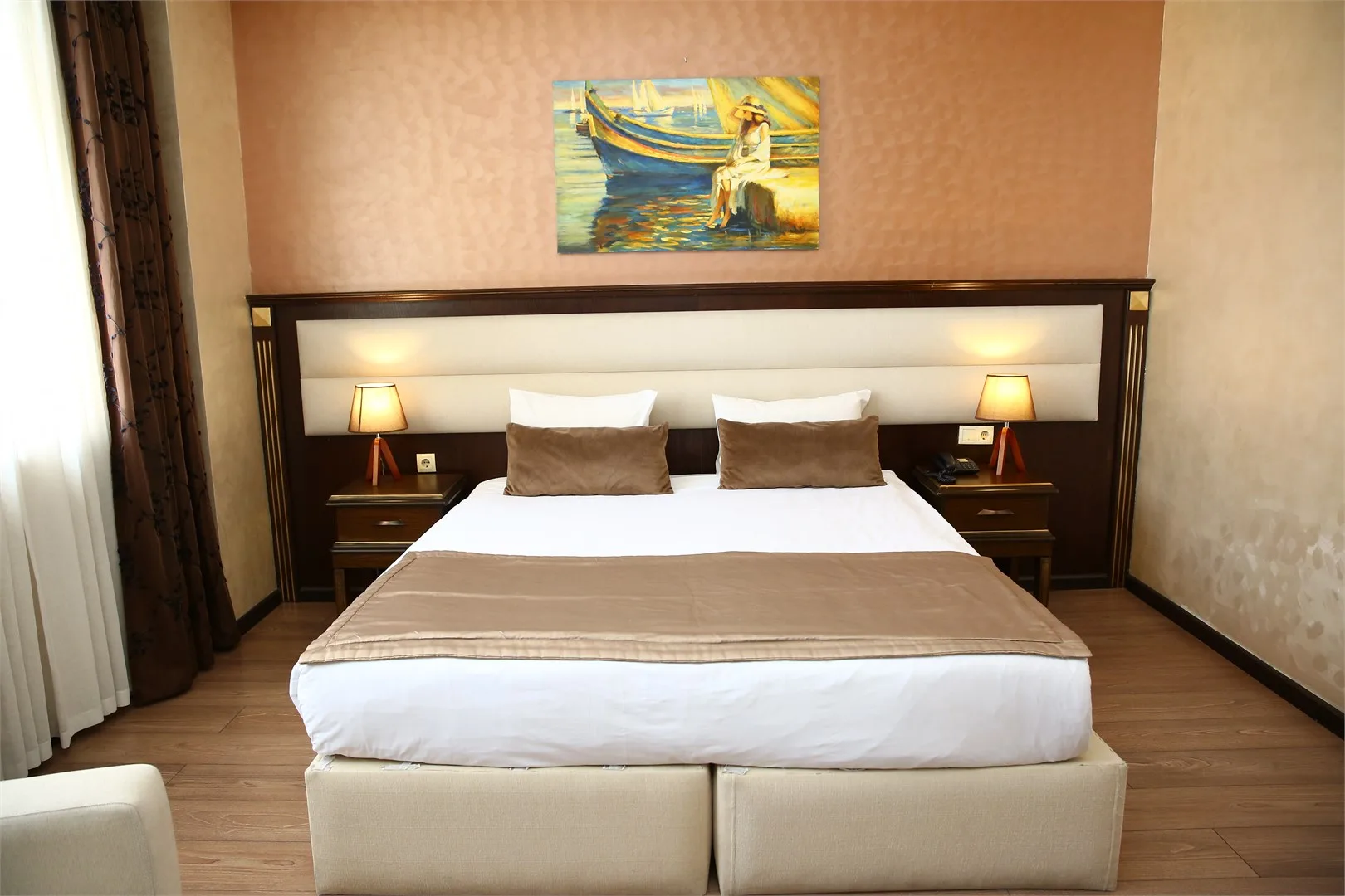 Espacio representativo del hotel: Un dormitorio con una cama bien tendida, mesas de noche a juego y un cuadro enmarcado.