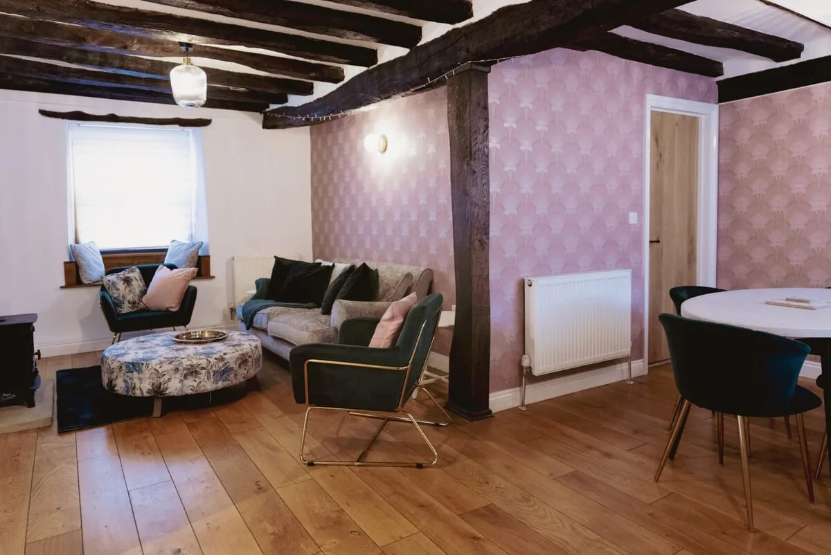 Sala de estar y comedor con asientos, una mesa de centro redonda y vigas a la vista.