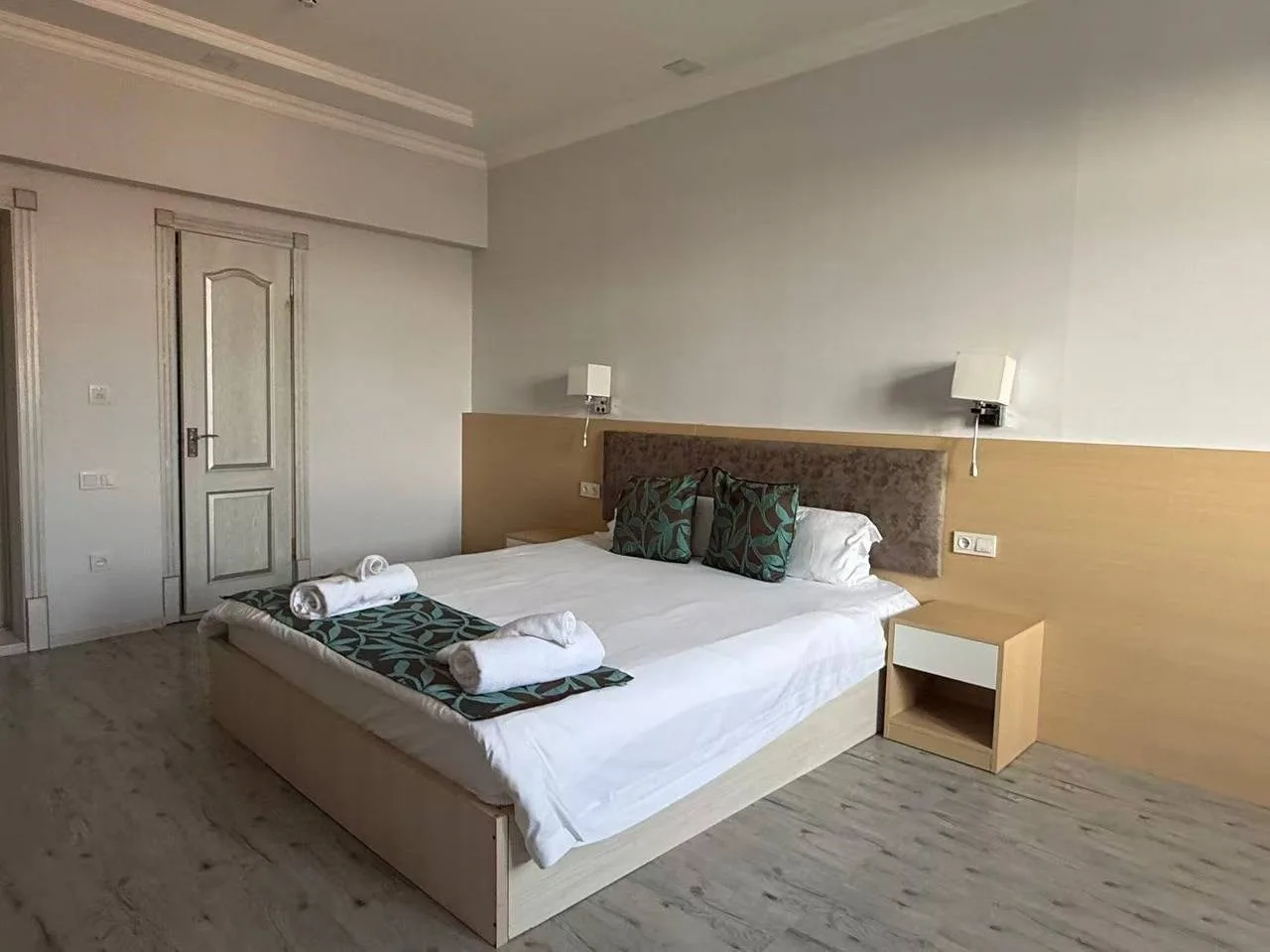 Espacio representativo del hotel: Un dormitorio con una cama bien tendida y un cabecero de madera clara.