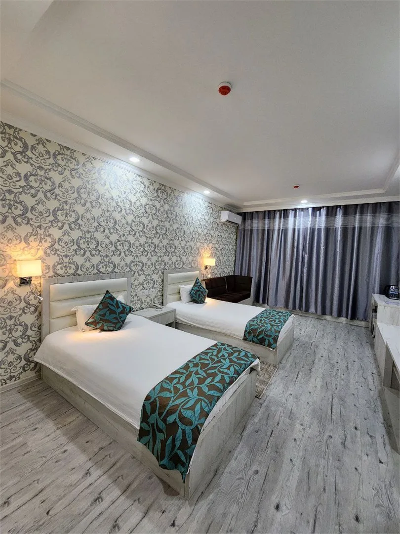 Espacio representativo del hotel: Dormitorio con dos camas, papel tapiz estampado y cortinas en la pared del fondo.