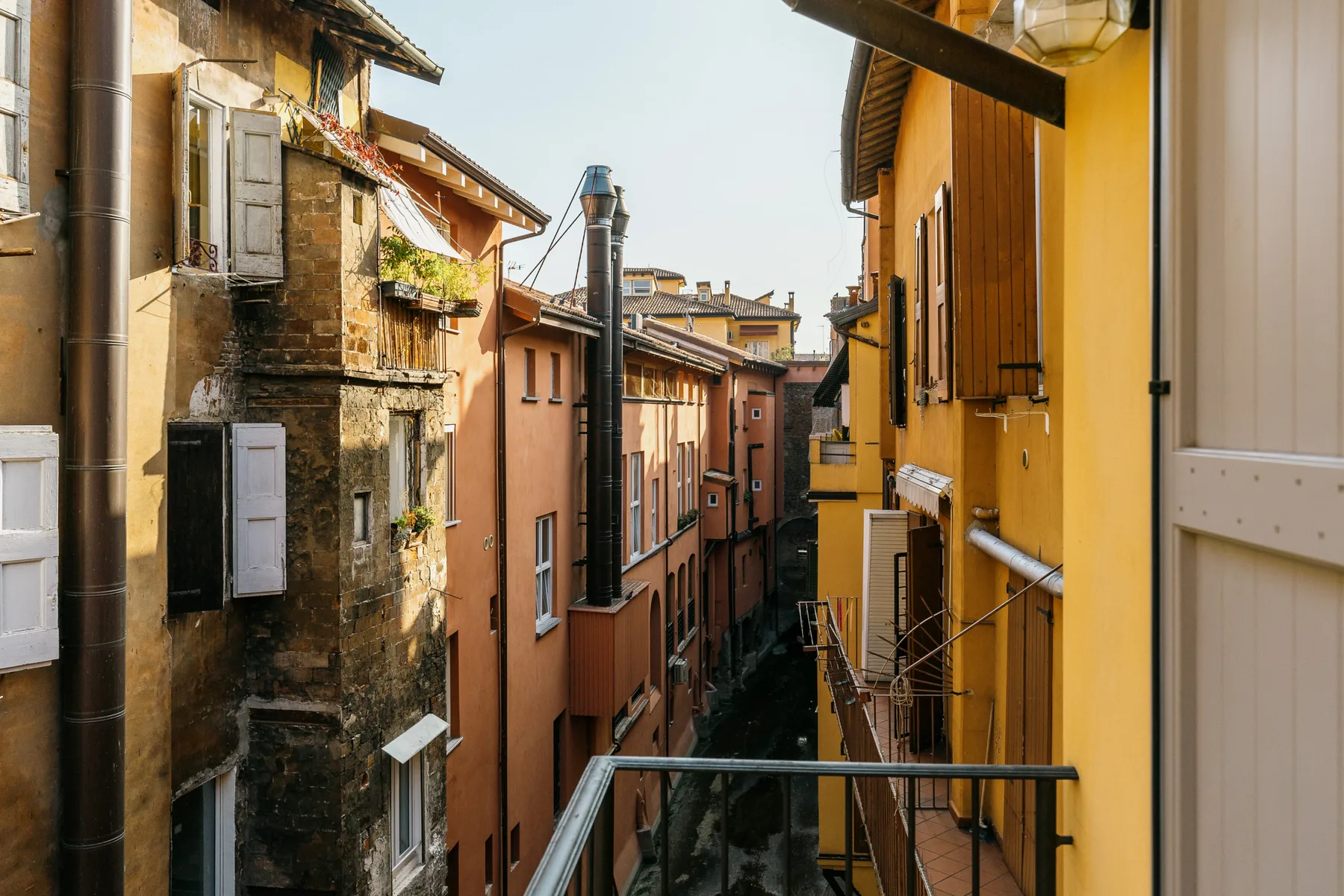 Una calle estrecha pasa entre edificios cercanos con fachadas coloridas y ventanas con contraventanas.