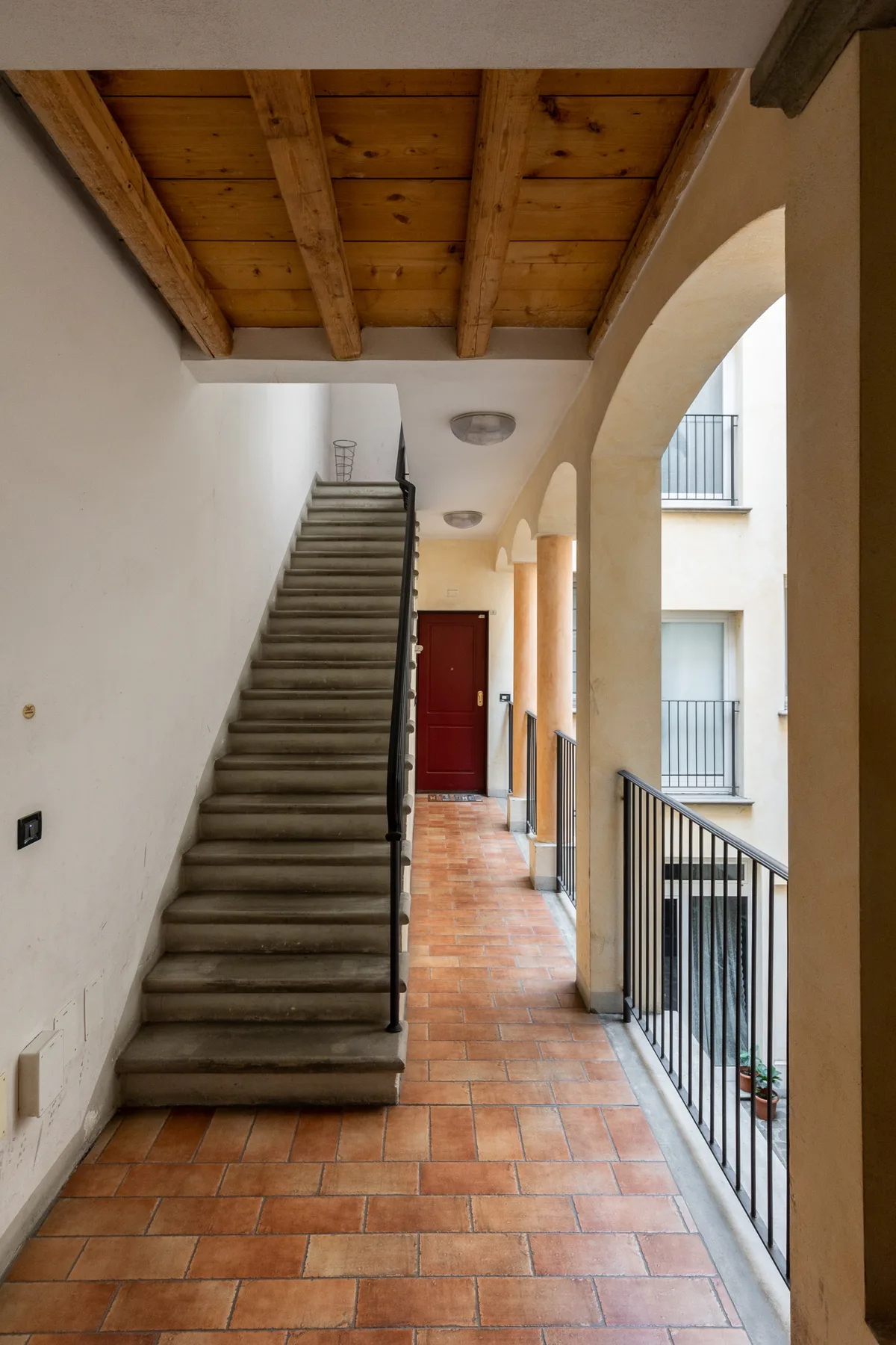 Zona común: Un pasillo embaldosado con una escalera, arcos y un techo de madera.