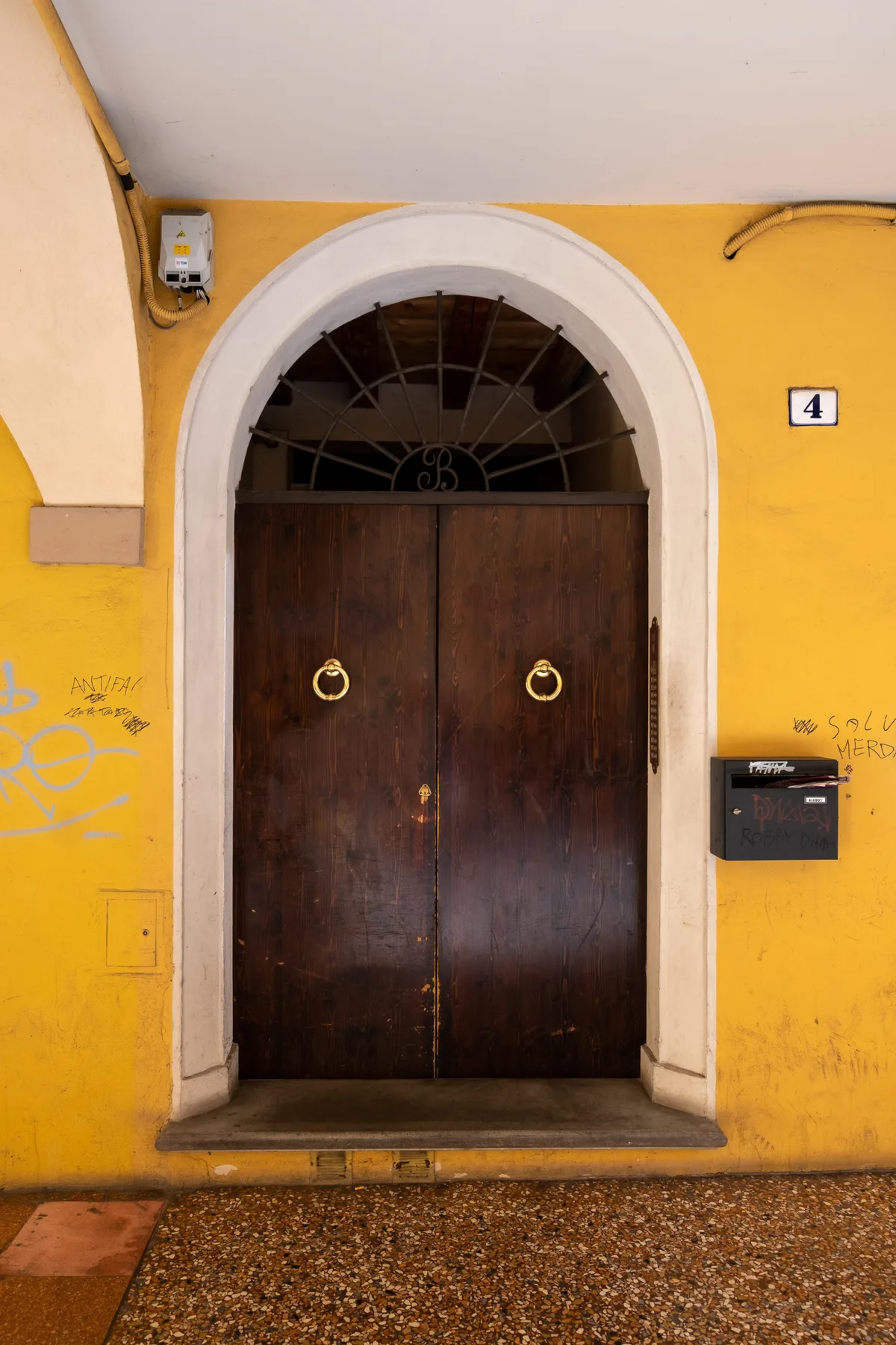 Zona común: Una puerta de entrada oscura y arqueada en una pared amarilla.