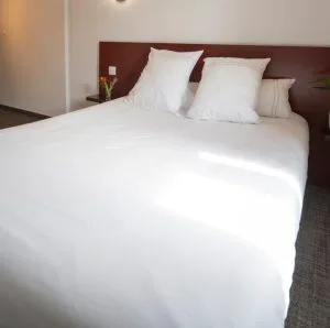 Representative hotel space: A neatly made bedroom bed with white bedding and pillows.
