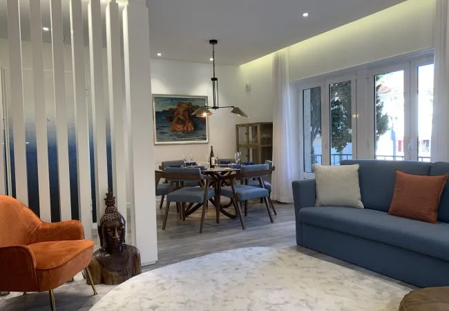 A bright living and dining area with a blue sofa beside a dining table.