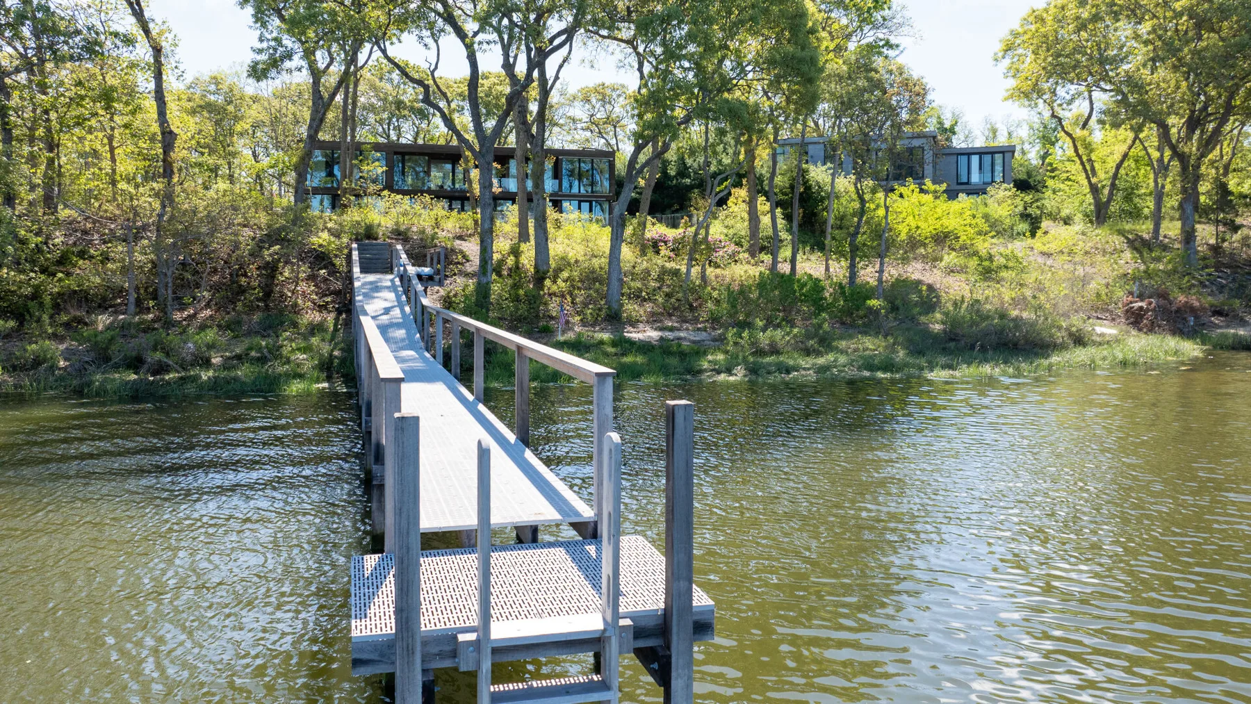 A narrow dock extends across the water toward a wooded shoreline.
