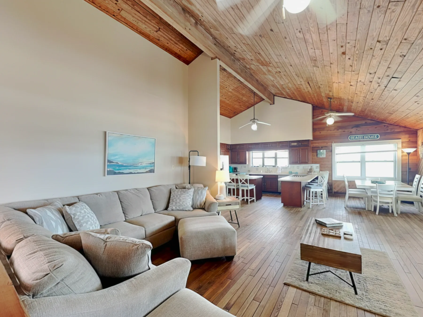 A spacious living area with seating, a coffee table, and a kitchen in the background.