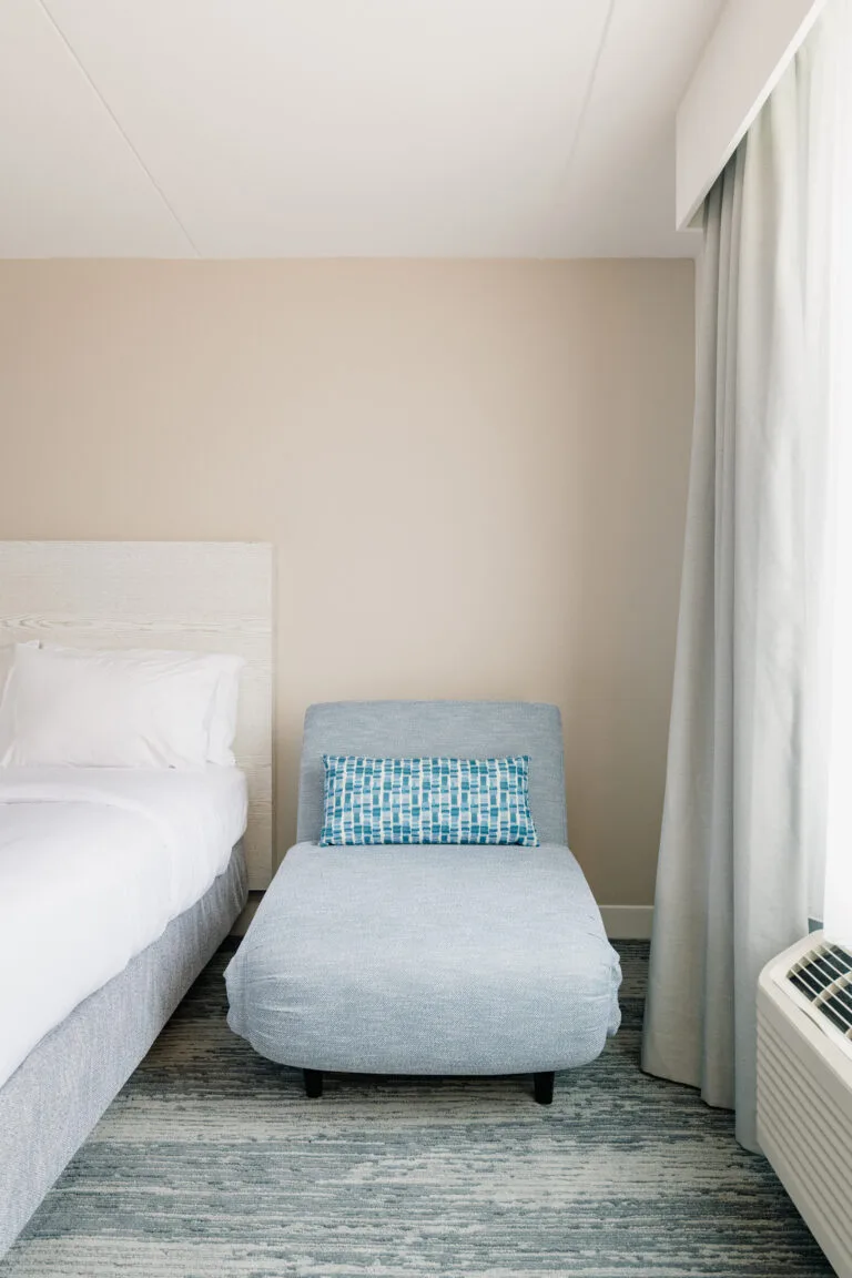 Representative hotel space: A bedroom with a bed, upholstered seating, and a curtained window.