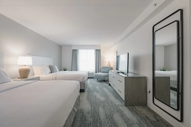 Representative hotel space: A bright bedroom with two beds, a television, and a large mirror.