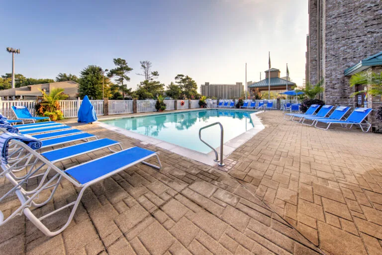 Representative hotel space: Outdoor swimming pool surrounded by blue lounge chairs and a paved deck.