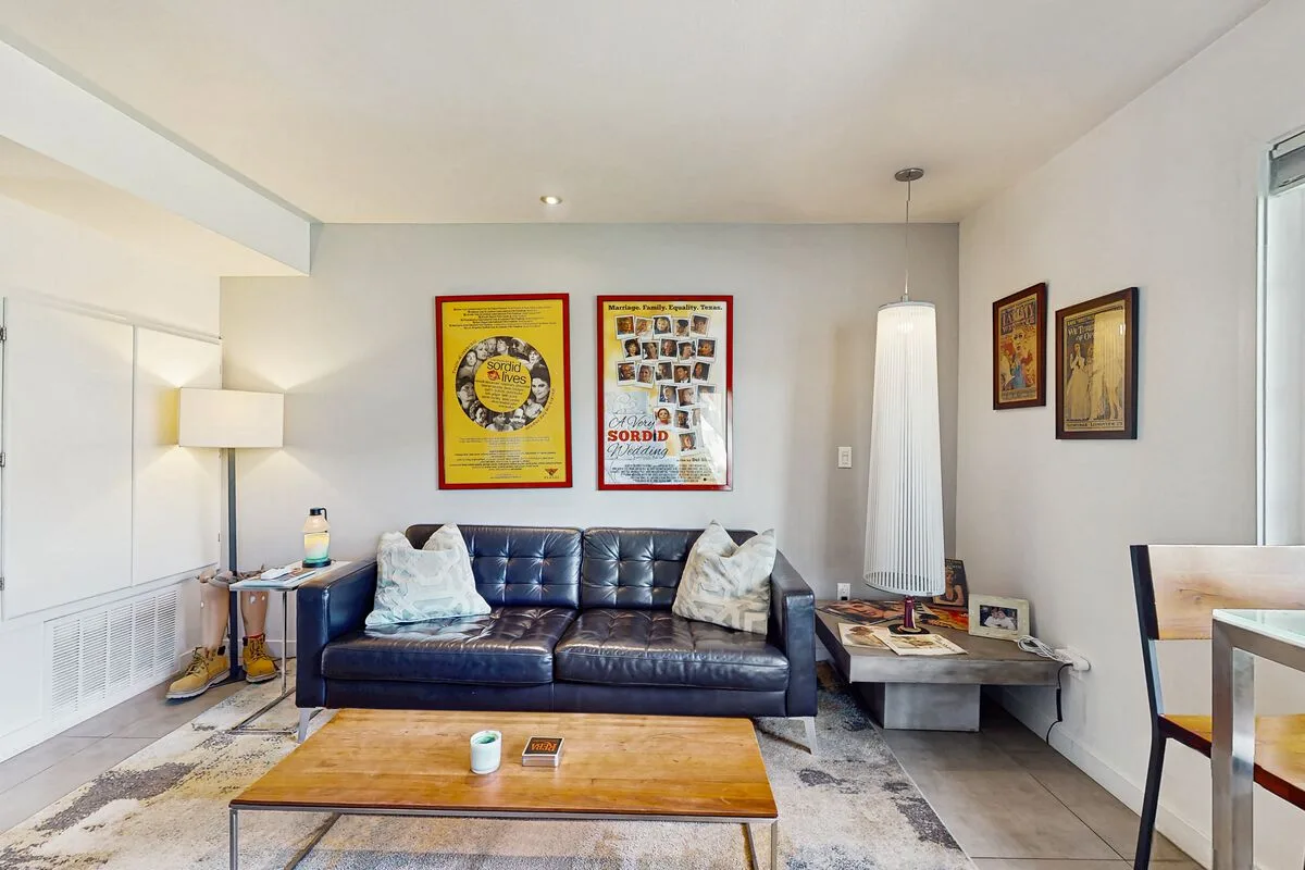 A living room with a dark sofa, a low table, and colorful wall art.