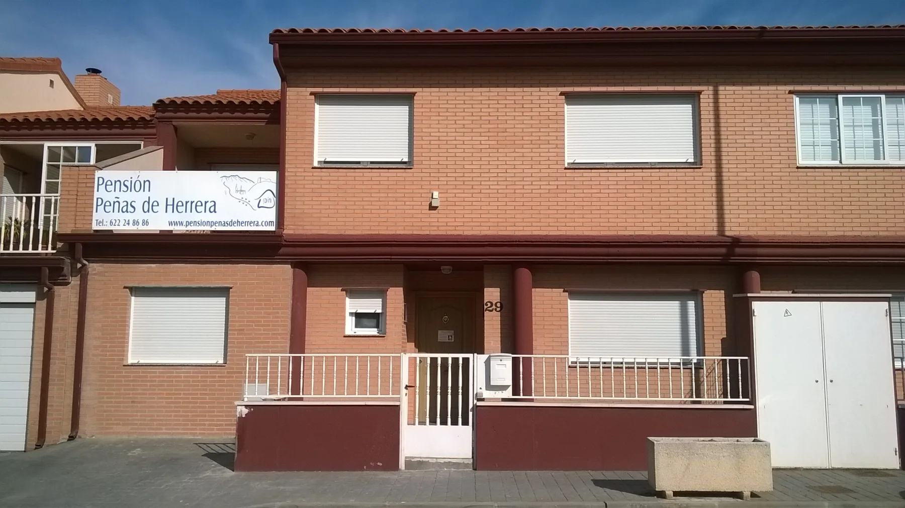 Espacio representativo del hotel: Exterior de una casa de huéspedes de ladrillo con balcones y ventanas con persianas.