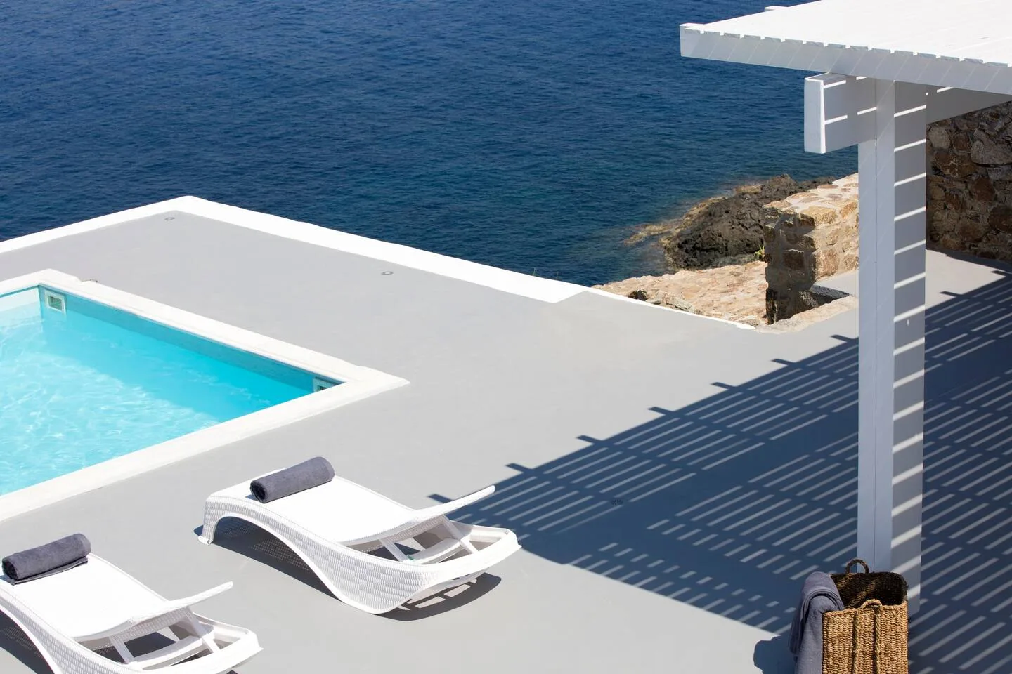 A seaside pool deck with lounge seating and open water beyond.