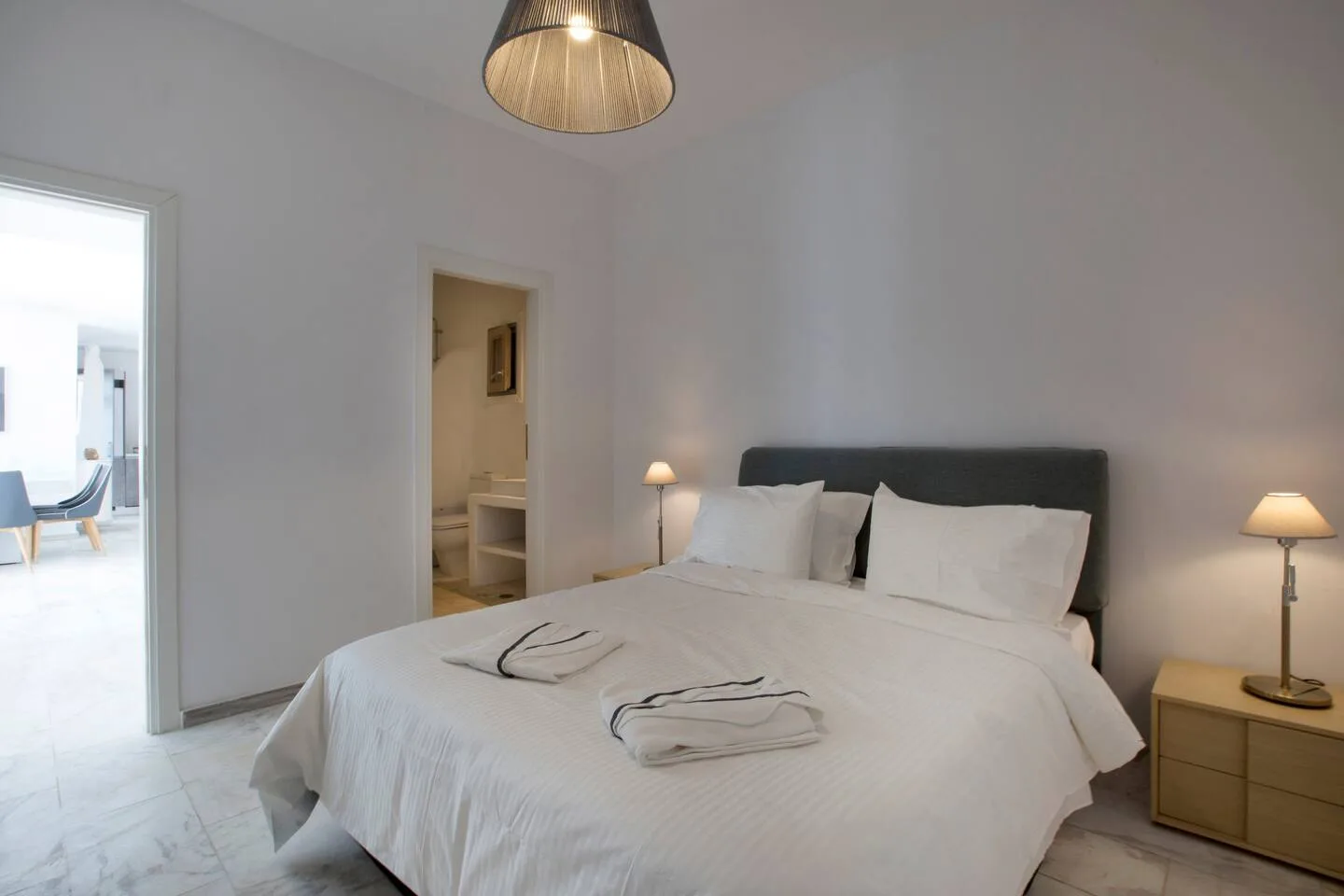 A bright bedroom with a neatly made bed and bedside lamps.