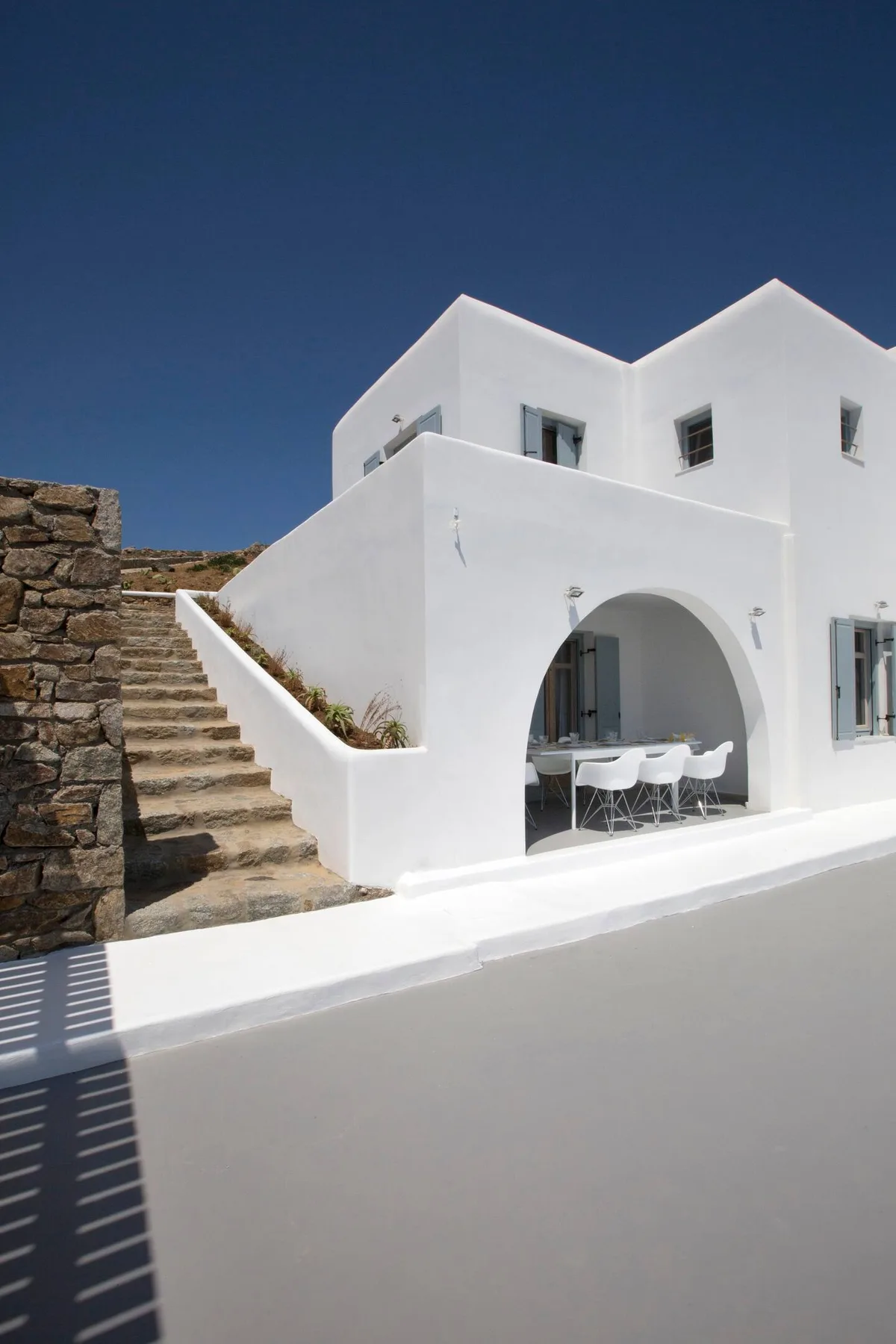 A white building with an arched patio opening and outdoor dining seating.