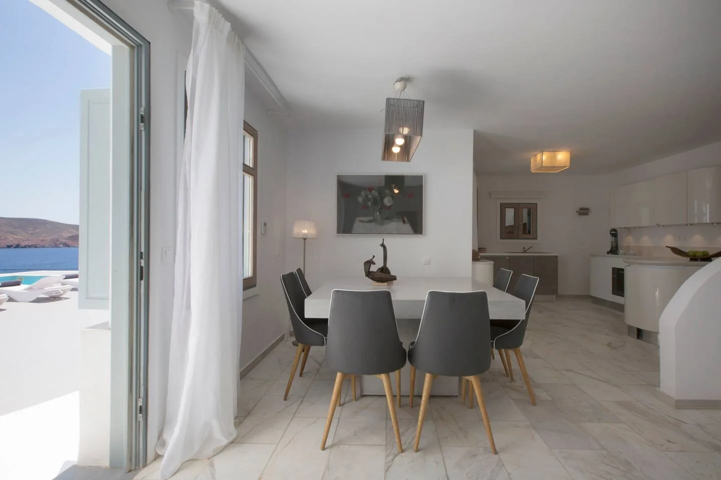 A dining area with a table and chairs beside an open patio doorway.