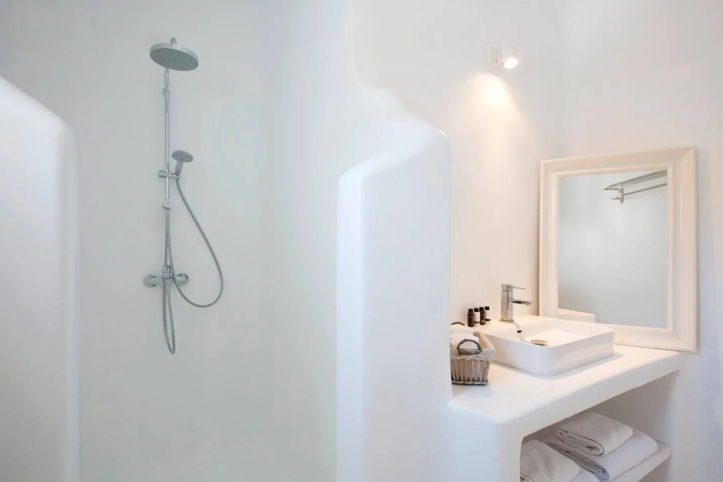 A bright bathroom with a shower and a sink beneath a framed mirror.