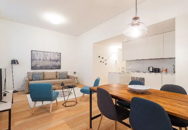 An open-plan living and dining area with a kitchen and wooden dining table.