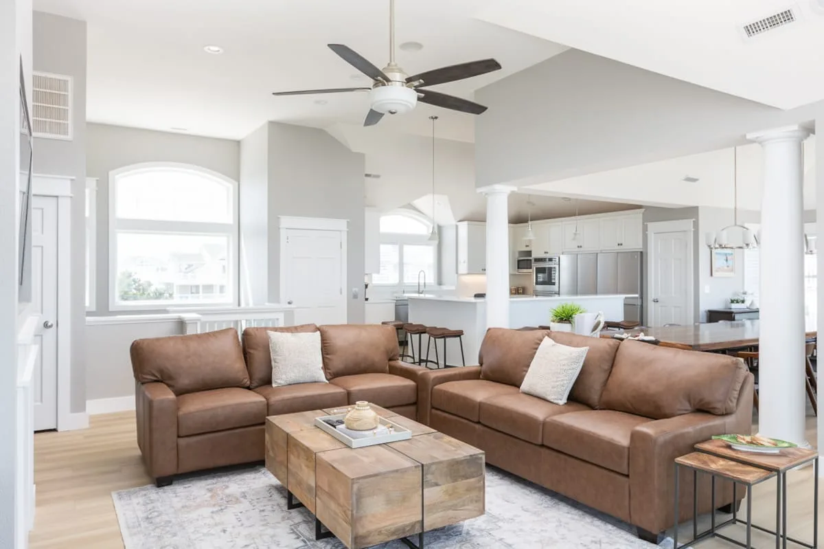 A bright open-plan living room with brown seating and a coffee table.