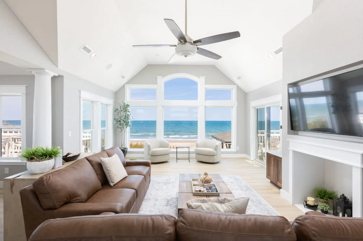 A bright living room with seating and large windows overlooking the ocean.