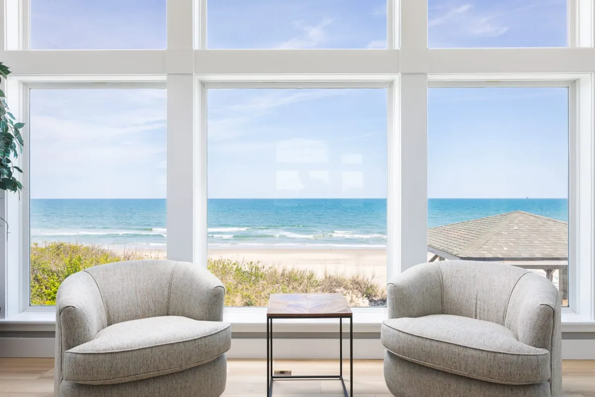 A bright sitting area with two chairs facing large windows overlooking the beach.