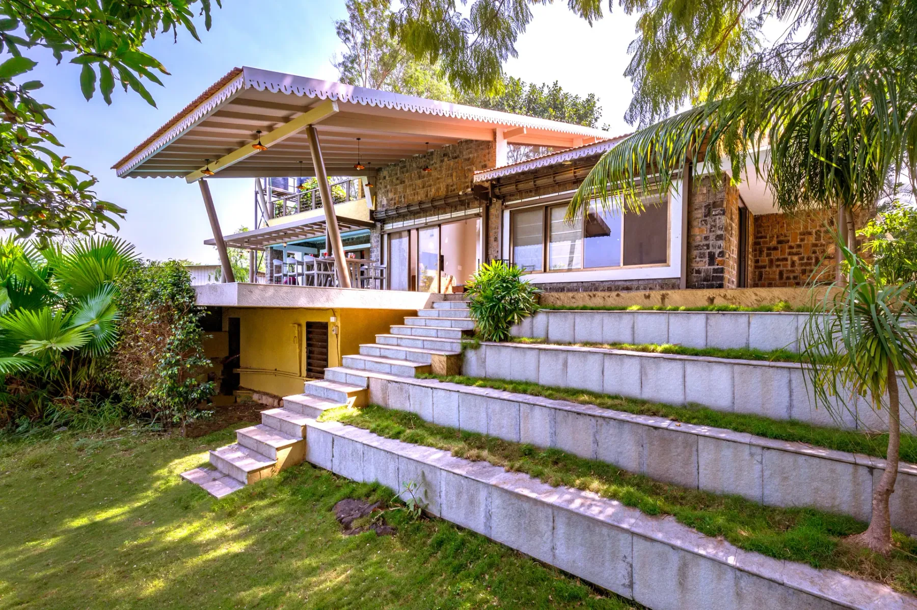 A landscaped exterior view of a house with broad steps leading to a covered patio.