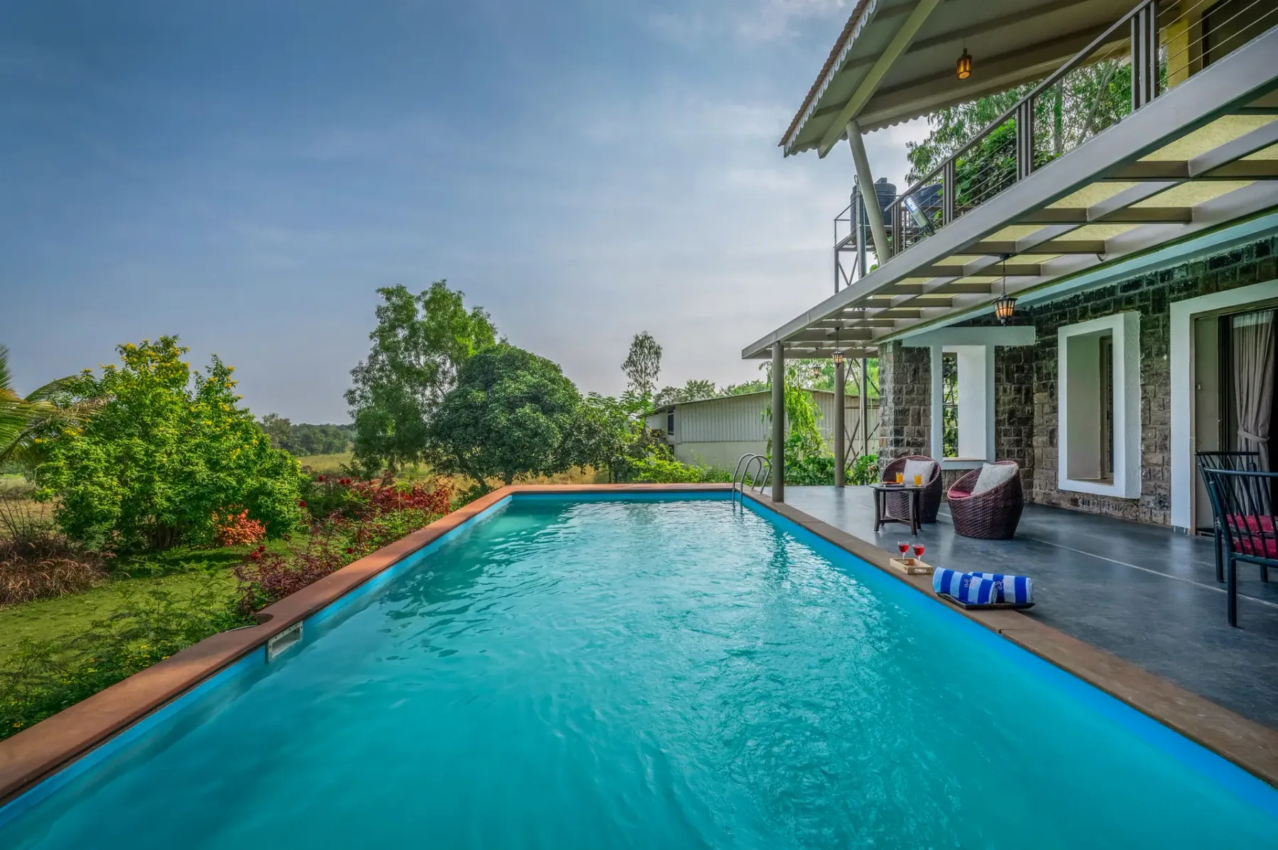 A swimming pool beside a modern building, with outdoor seating and greenery.