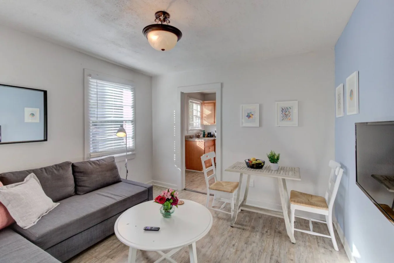 A bright living area with seating, a round coffee table, and a dining table.