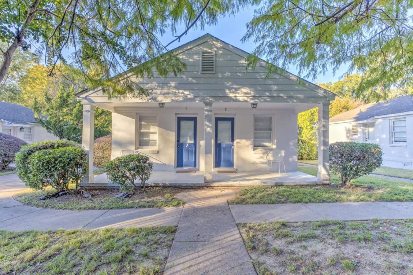 Shared amenity: A small white building with two blue doors sits beside a paved walkway.
