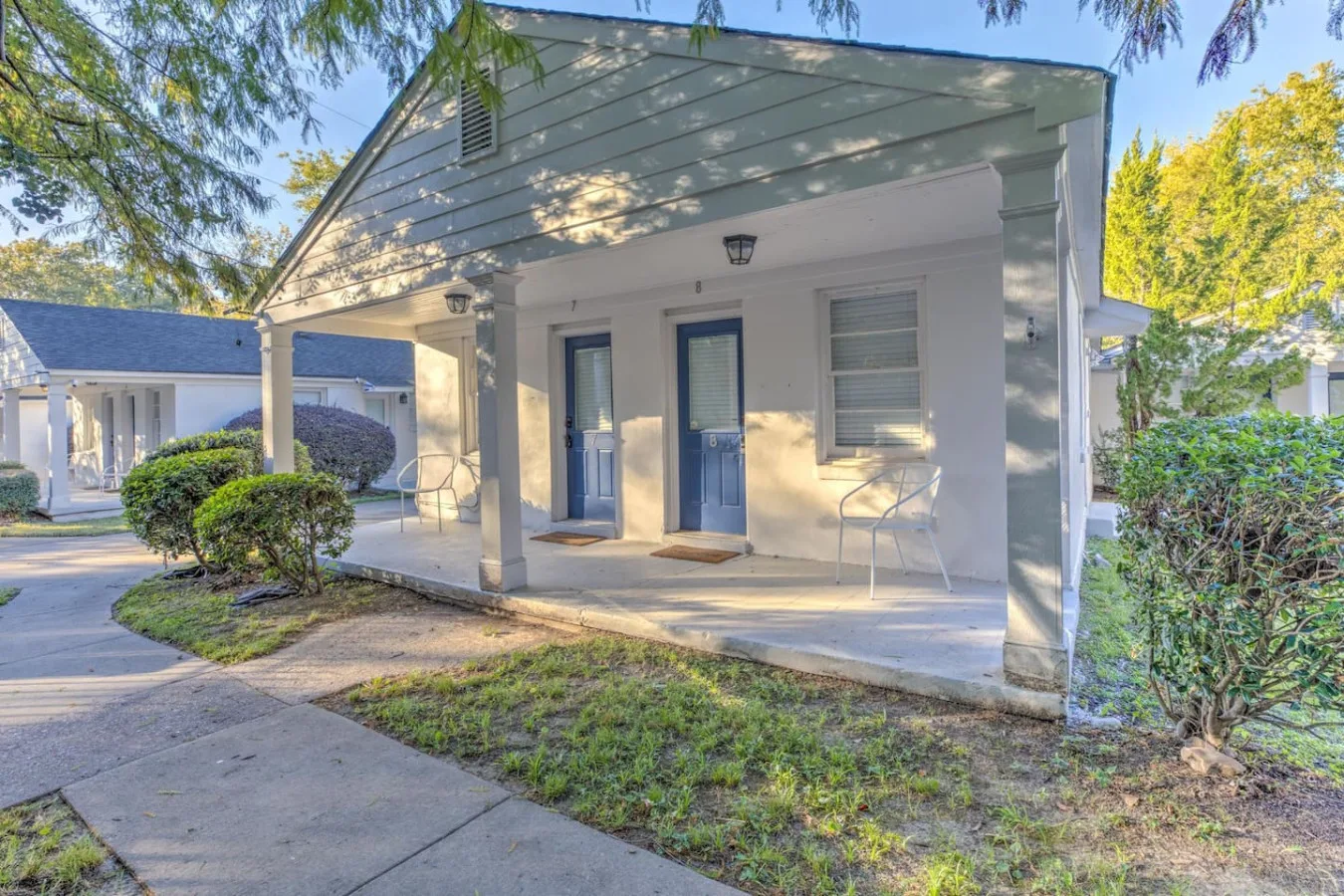 Shared amenity: A covered porch with two blue doors and a paved walkway.
