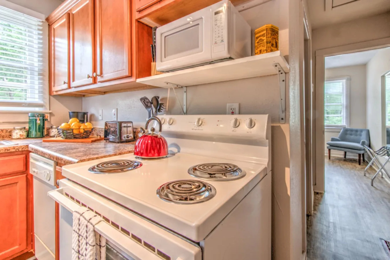 A kitchen with a white stove, microwave, and wooden cabinets.