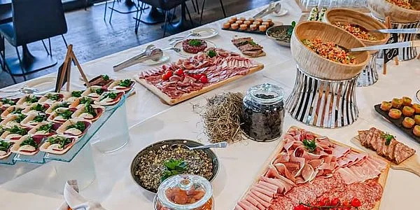 Espacio representativo del hotel: Una mesa de bufé presenta platos fríos variados, carnes en lonchas y pasteles.