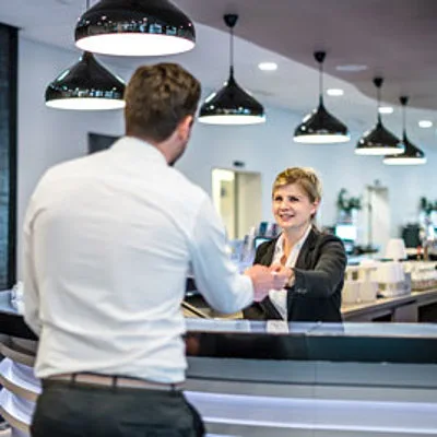 Espacio representativo del hotel: Un mostrador de recepción de hotel donde una empleada atiende a un huésped.