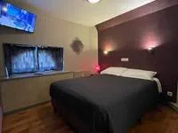 Espacio representativo del hotel: Un dormitorio con una cama, una pared oscura y un televisor.