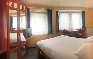 Espacio representativo del hotel: Un dormitorio con una cama, ventanas con cortinas y un televisor.