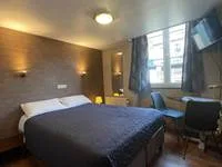 Espacio representativo del hotel: Un dormitorio de hotel con cama, luces de noche y una ventana.