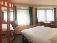 Espacio representativo del hotel: Un dormitorio con una cama grande y ventanas con cortinas.