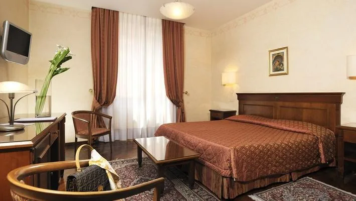 Representative hotel space: A bedroom with a large bed, a window, and a small seating area.