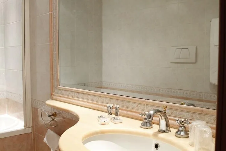 Representative hotel space: A bathroom vanity with a sink, faucet, and large wall mirror.