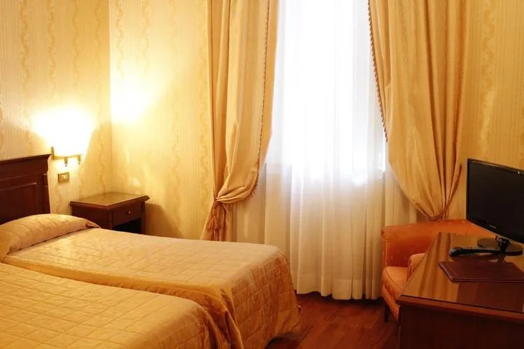 Representative hotel space: A bedroom with two beds beside a curtained window.