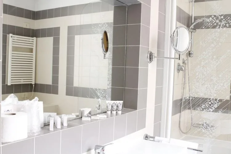 Representative hotel space: A tiled bathroom with a shower and a wide mirror above the sink.