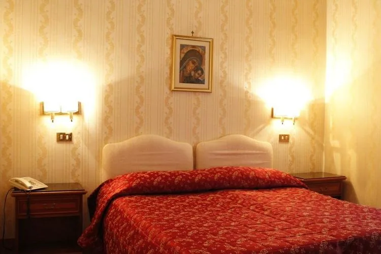 Representative hotel space: A bedroom with a red patterned bedspread and matching bedside tables.