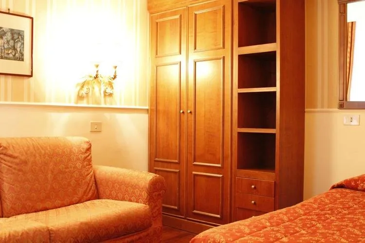 Representative hotel space: A bedroom with a patterned bed and a wooden wardrobe.