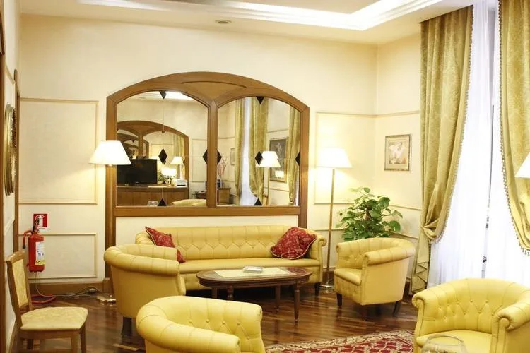 Representative hotel space: A hotel lounge with upholstered seating, a coffee table, and tall curtained windows.