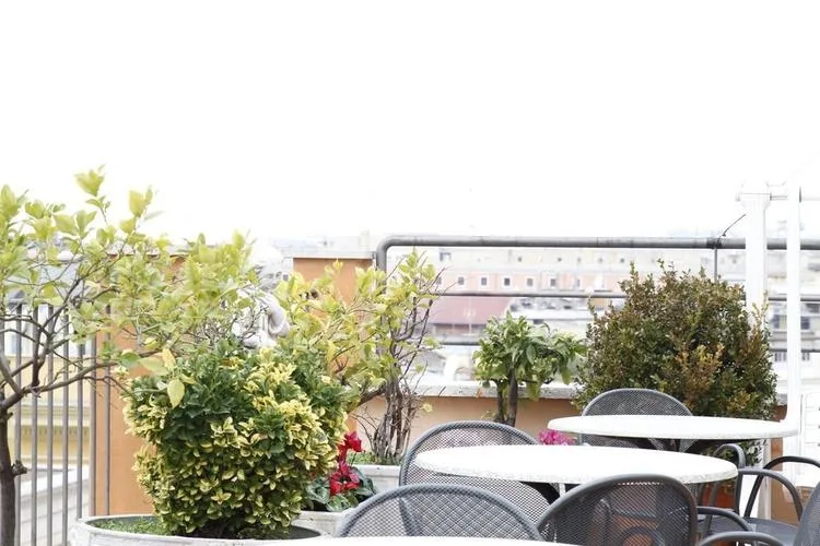 Representative hotel space: An outdoor patio with round tables and seating among potted plants.