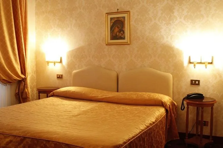 Representative hotel space: A warmly lit bedroom with a large bed and framed picture above the headboard.