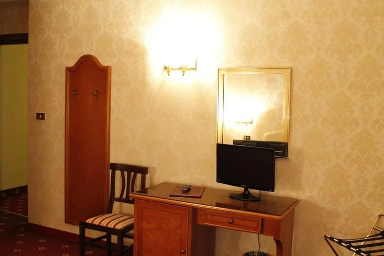 Representative hotel space: A warmly lit room with a wooden desk, television, and chairs.