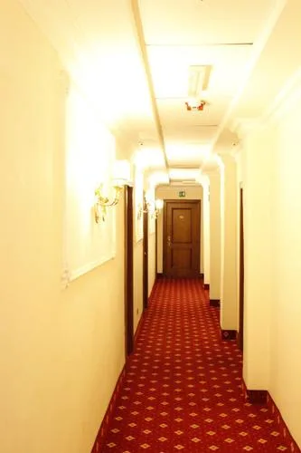 Representative hotel space: A hotel hallway with patterned red carpet and doors along the corridor.