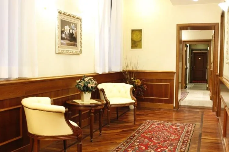 Representative hotel space: A furnished hallway has wood paneling, seating, and a patterned rug.