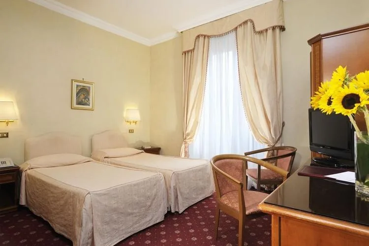 Representative hotel space: A bedroom with two beds, a window, and seating.